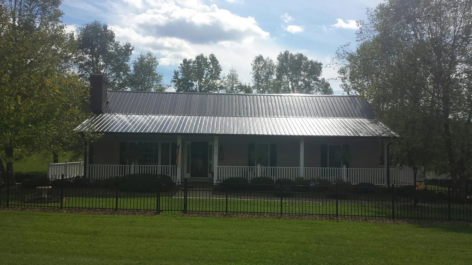 Gray metal roof on a brick ranch with a full width front porch — Gutter Guard Installation work by our crew in Whitehall