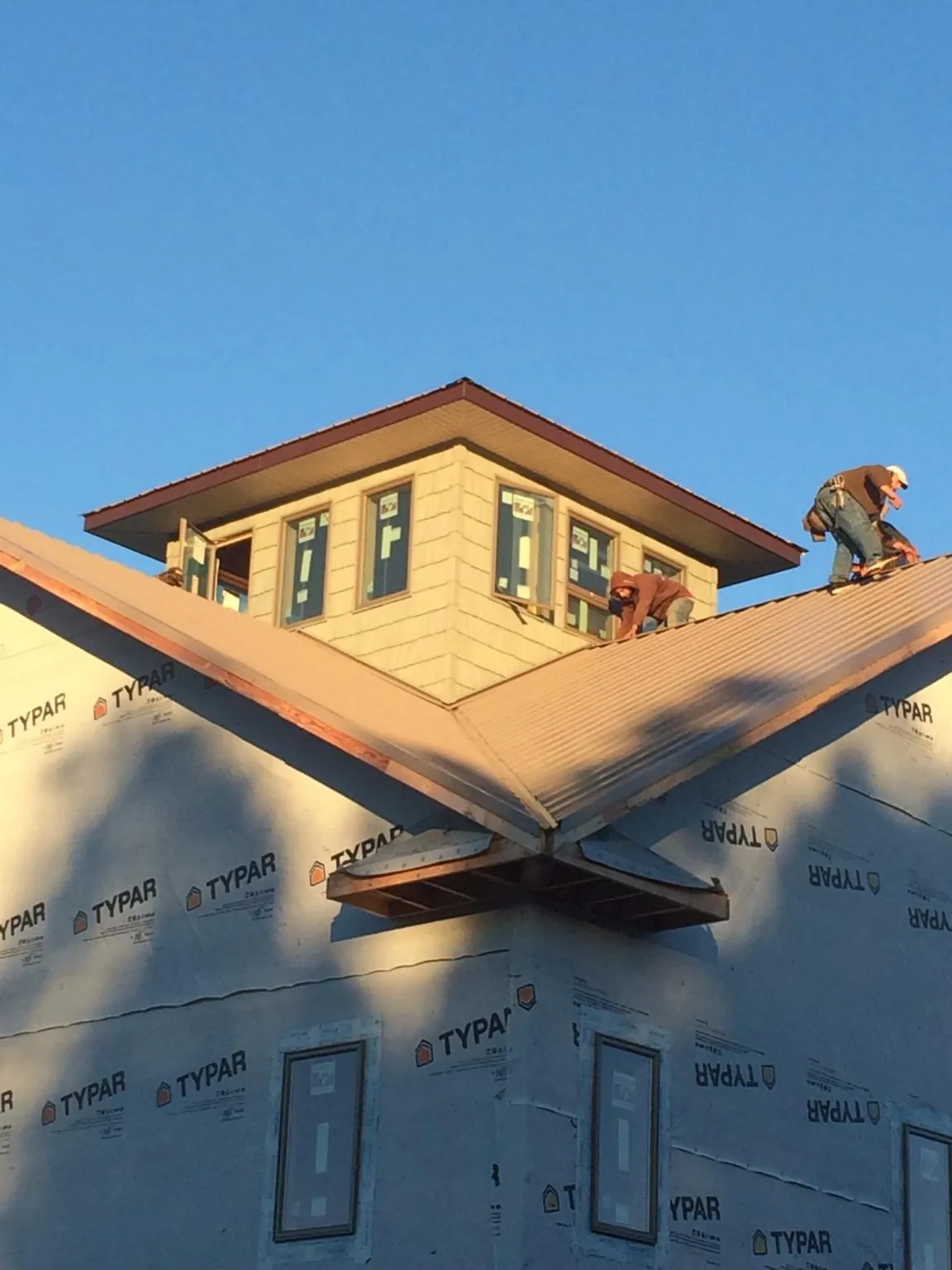 Roofers working around a rooftop cupola on a new metal roof at sunset — Roof Waterproofing in Whitehall by Roofing Brothers